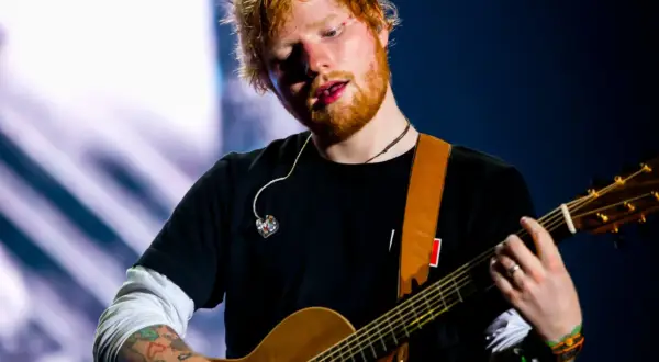 Ed Sheeran gra na gitarze akustycznej na scenie.
