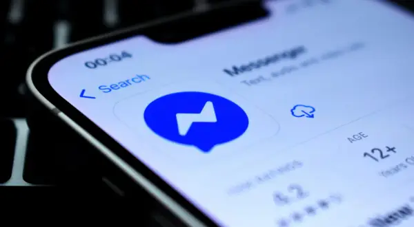Ikona aplikacji Messenger na ekranie telefonu. Widoczne dymki czatu, wyszukiwarka i informacja o wieku 12+.