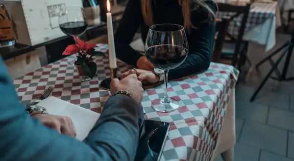 Para przy świecach, wino, dłonie splecione. Czy jemu na mnie zależy? Romantyczny wieczór w restauracji.