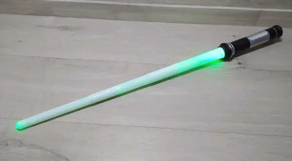 Zielony miecz Star Wars leży na drewnianej podłodze.