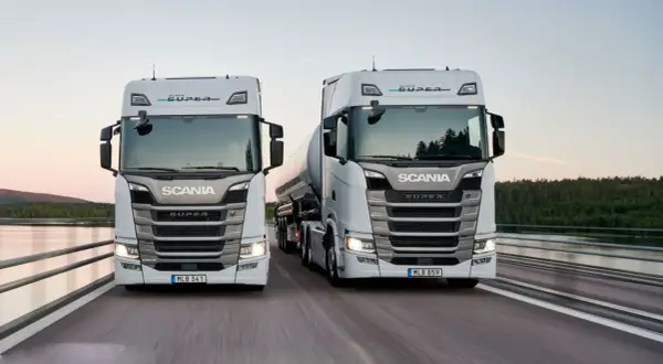 Två nya Scania lastbilar, en med tank, kör på en bro. Kolla in ny Scania lastbil pris för din nästa transport.