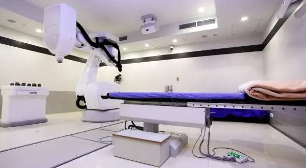Ein CyberKnife-Behandlungsraum mit Roboterarm und Liege. Mögliche CyberKnife Nachteile sind die Kosten und die Notwendigkeit präziser Planung.