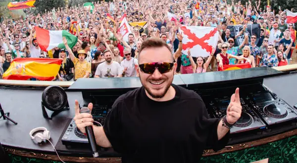 DJ Skytech rozkręca tłum na festiwalu, wśród flag Hiszpanii i Włoch.