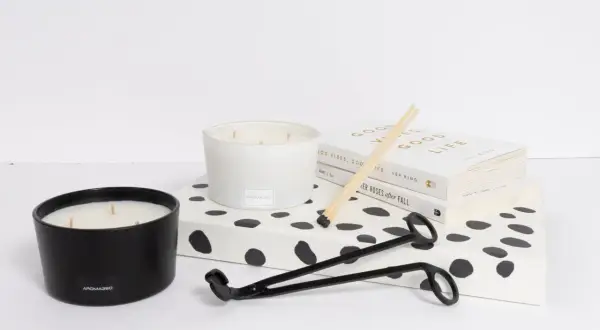 Candle care essentials: two candles, a wick trimmer, matches, and books. Learn how to remove candle wax for a cleaner burn.
