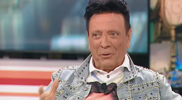 Rupert, el peluquero, luce una chaqueta vaquera tachonada y una camiseta con un rostro.