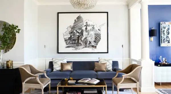 Elegant vardagsrum med en djupblå soffa som blickfång. En stor svartvit tavla och en kristallkrona ger inspiration.
