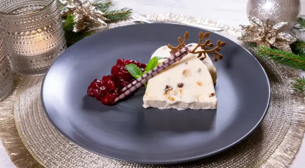 Ein festlicher weihnachts nachtisch: Eisparfait mit Beerenkompott, Schokoladenstäbchen und Rentiergeweih-Dekoration.