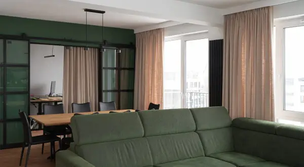 Jasne zasłony pięknie komponują się z zieloną kanapą, tworząc przytulną atmosferę. Idealne pytanie: jakie zasłony do zielonej kanapy?