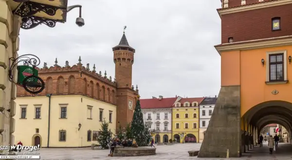 Rynek w Tarnowie zimową porą. W centralnym punkcie placu stoi choinka, a w tle widać zabytkowe kamienice i wieżę ratuszową.
