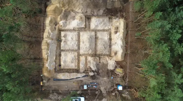 Budowa fundamentów domu w lesie. Widać zbrojenie i szalunki. To etap prac poprzedzający badania geotechniczne gruntu.