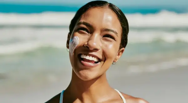 Strahlendes Lächeln am Strand, Sonnencreme schützt vor Hautalterung.