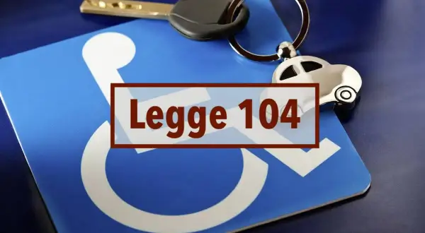 Chiave e portachiavi a forma di auto su un cartello blu con simbolo disabili e testo "Legge 104".