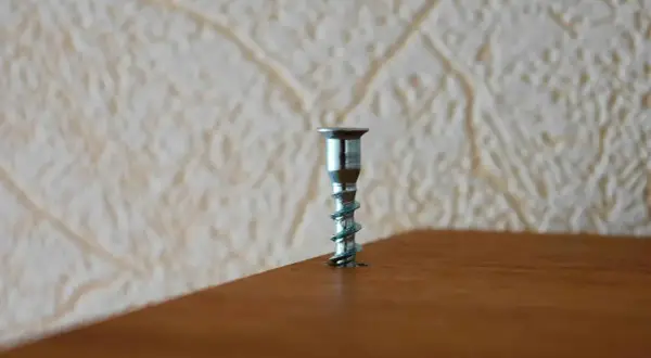 A metal screw is stuck in a wooden surface. This image might be useful for a guide on how to remove stuck screws.