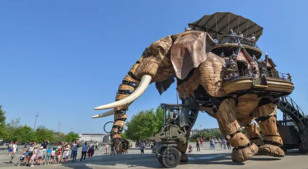 Le Grand Éléphant mécanique se promène sur l'île de Nantes, transportant des visiteurs émerveillés dans sa structure en bois.