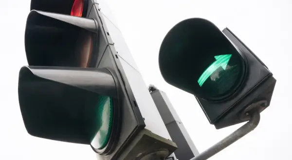Zielona strzałka warunkowa świeci, sygnalizując możliwość skrętu. Obok czerwone światło.