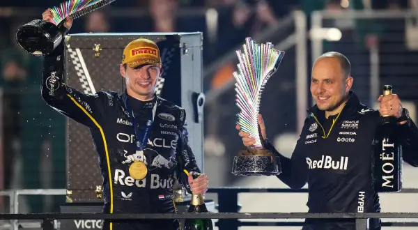 Max Verstappen celebra con un trofeo y champán, junto a Gianpiero Lambiase, tras una victoria.