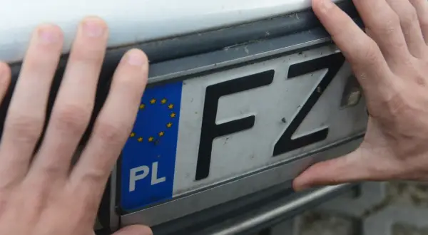Dłonie trzymają tablicę rejestracyjną z literami FZ. Jaka to rejestracja?