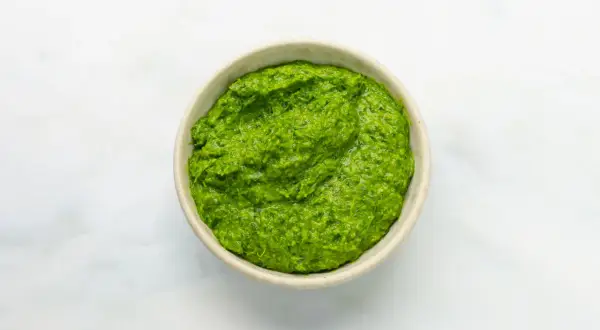 Eine Schüssel mit leuchtend grüner Salsa verde, die frisch und würzig aussieht.