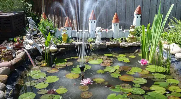 Un bassin avec nénuphars, fontaine et décorations de château. Idéal pour fabriquer cache filtre bassin.
