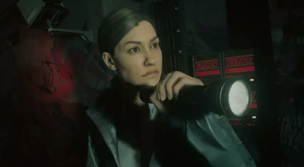 Saga Alan Wake 2 DLC: Agentka z latarką bada mroczne korytarze, gdzie migają czerwone napisy "EMERGENCY - SEEK SHELTER".