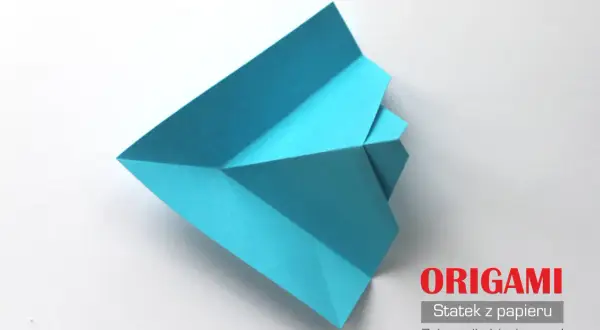 Niebieski statek z papieru złożony techniką origami na białym tle.