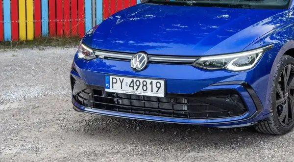 Niebieski Volkswagen z tablicą PY 49819, zaparkowany przy kolorowym płocie.