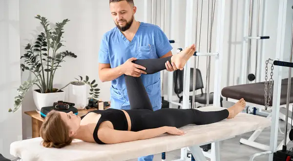Fizjoterapeuta wykonuje test Thomasa, pomagając pacjentce w rehabilitacji.