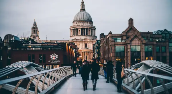 Ludzie spacerują po moście w Londynie, podziwiając katedrę św. Pawła i budynki City of London School. To fascynująca podróż przez londyńską historię.