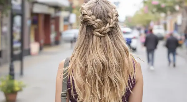 Einzigartige Frisur: Haare flechten zu einem Kranz über blondem Haar, während die Trägerin durch eine belebte Straße geht.