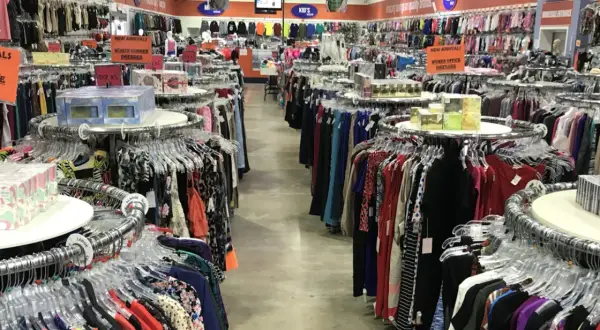 Pasillos llenos de ropa en una tienda, ideal para aprender como montar una tienda de ropa de segunda mano.