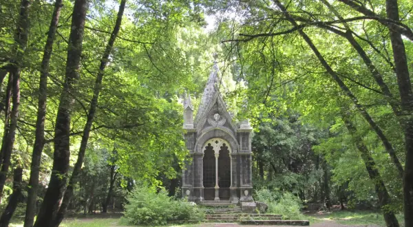 Un piccolo tempietto gotico nel **bosco delle fate a Torre Alfina**, circondato da alberi rigogliosi e sentieri ombrosi.