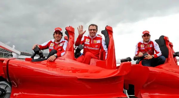 Trzech mężczyzn w strojach Ferrari siedzi w czerwonym wagoniku, który wygląda jak najszybszy rollercoaster na świecie.