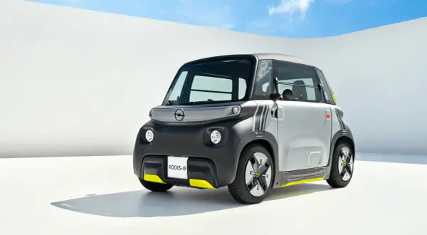 Najmniejszy Opel, Rocks-e, z żółtymi akcentami, prezentuje się nowocześnie na tle białej ściany i błękitnego nieba.