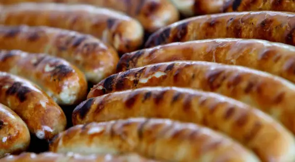 Reife Bratwürste auf dem Grill, die Frage "woher kommt die Bratwurst" wird hier kulinarisch beantwortet.