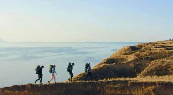 Fyra vandrare med ryggsäckar går längs en klippkant vid havet. En fantastisk vandring i Europa.