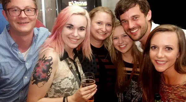 Glada vänner på en pub crawl i Stockholm. En kvinna med rosa hår håller ett glas öl.