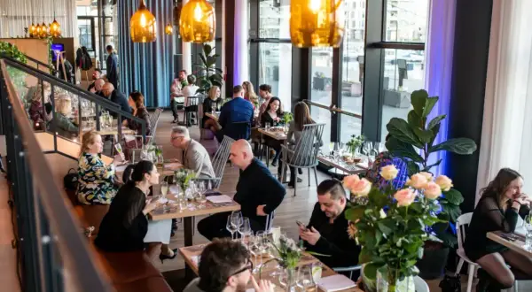 W restauracji "Polskie Smaki" goście delektują się posiłkami przy elegancko nakrytych stołach, w otoczeniu nowoczesnego wystroju i ciepłego światła.