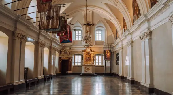Wnętrze klasztoru na Jasnej Górze, gdzie można podziwiać liczne częstochowa atrakcje, w tym ołtarz i wiszące sztandary.