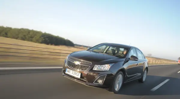 Brązowy Chevrolet Cruze 1.8 benzyna jedzie autostradą.