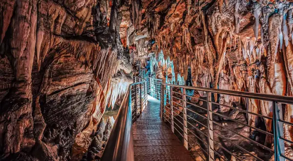 Sentiero illuminato tra stalattiti e stalagmiti nelle grotte in Toscana. Un viaggio sotterraneo tra formazioni rocciose millenarie.