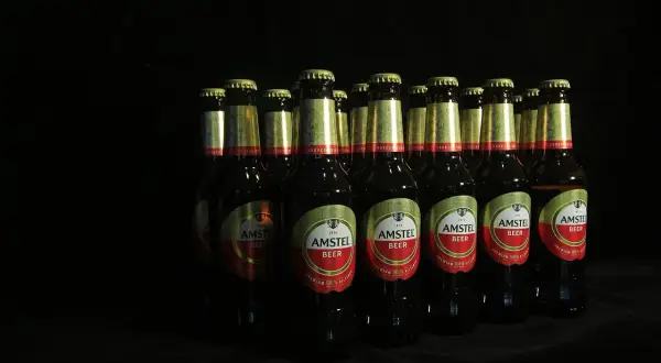 Rząd butelek piwa Amstel na czarnym tle. Czy piwo jest niezdrowe? To zależy od ilości.