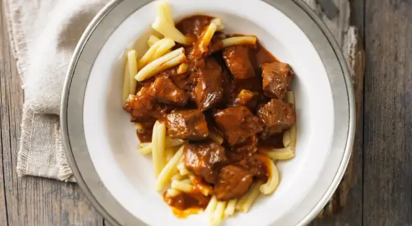 Herzhaftes Gulasch mit zarten Fleischstücken in würziger Sauce, serviert auf hellen Nudeln. Ein Klassiker, der zeigt, was ist Gulasch.