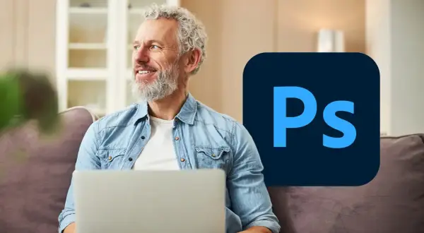 Uśmiechnięty mężczyzna z laptopem i logo Photoshopa.