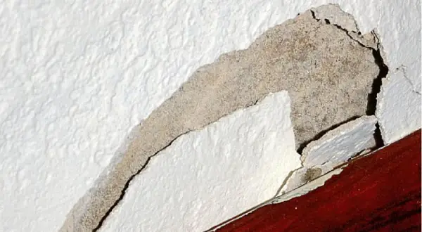 Odkruszający się tynk wewnętrzny, odsłaniający beton. Dowiedz się, jak naprawić odpadający tynk wewnętrzny.