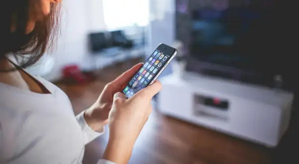 Kobieta przegląda aplikacje na telefonie, szukając sposobu, jak wyczyścić pamięć w telefonie, by zwolnić miejsce.
