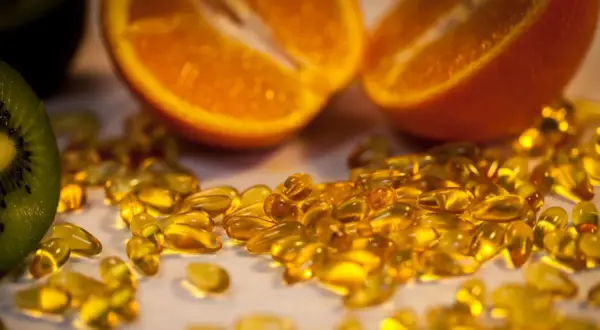 Orangenscheiben und Kiwi neben vielen gelben Kapseln. Die Wirkung von hochdosiertem Vitamin C für die Gesundheit.