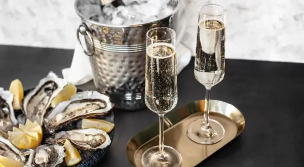 Austern mit Zitrone, Champagnergläser und Eis-Eimer mit Flasche.