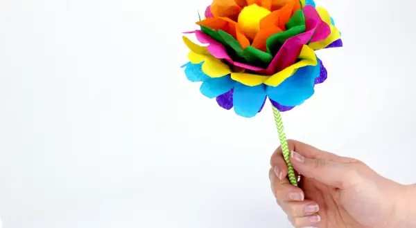 Une fleur en papier Canson facile, aux couleurs vives, tenue par une main.