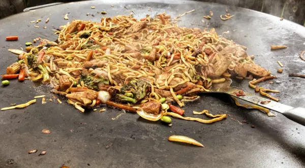 En wok med nudlar, kyckling och grönsaker tillagas på en muurikka. Ett perfekt recept för en muurikka wok!