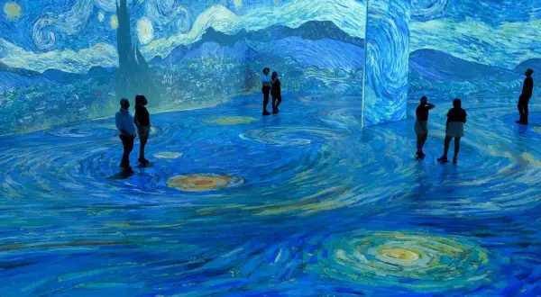 Visitors stand immersed in a swirling, starry landscape, a breathtaking projection of a Van Gogh painting.